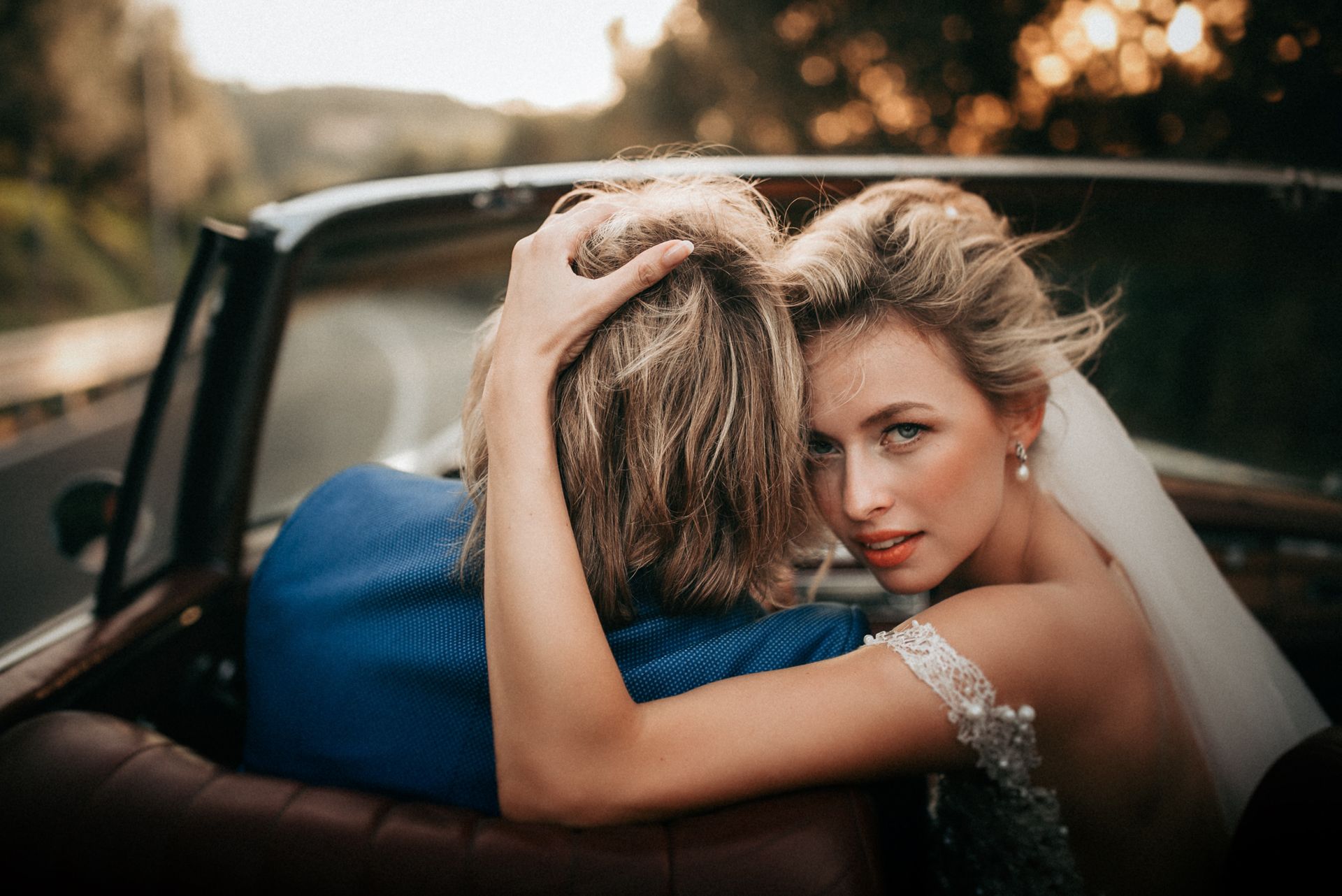 A bride and groom in wedding attire embrace in a dip while kissing on a stone terrace overlooking a coastal Italian town.