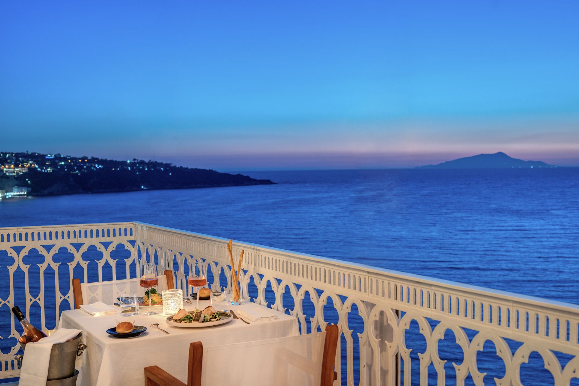 Terrazza del Vesuvio Restaurant sul mare al tramonto, con un tavolo apparecchiato che si affaccia sul mare blu e sulla costa in lontananza.