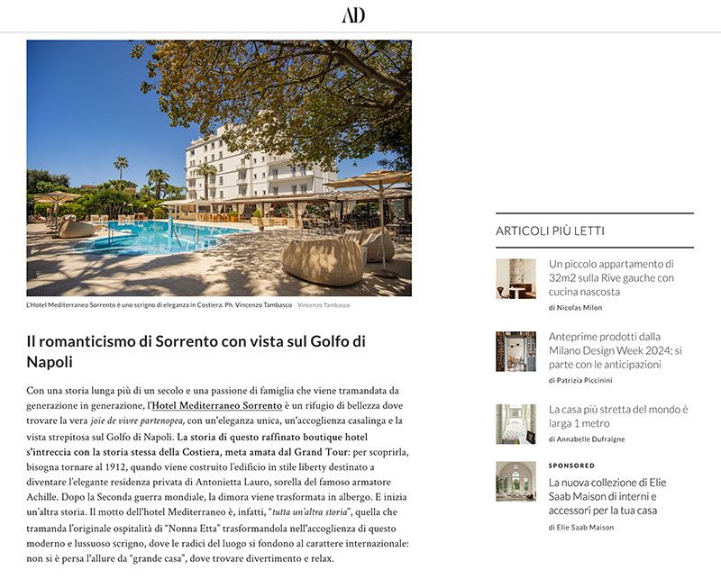 A white hotel building overlooking a swimming pool surrounded by lounge chairs and trees in Sorrento, Italy.