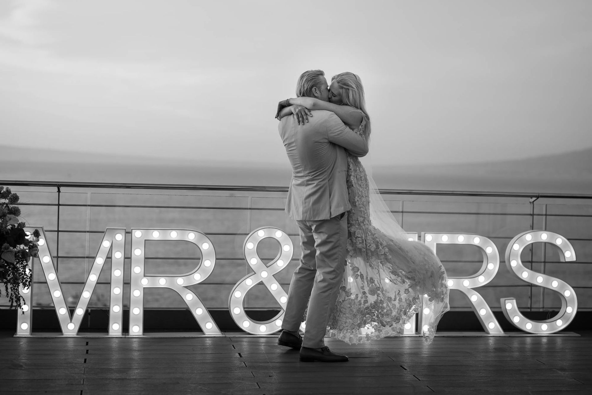 A couple embraces and kisses in front of large, glowing, illuminated 