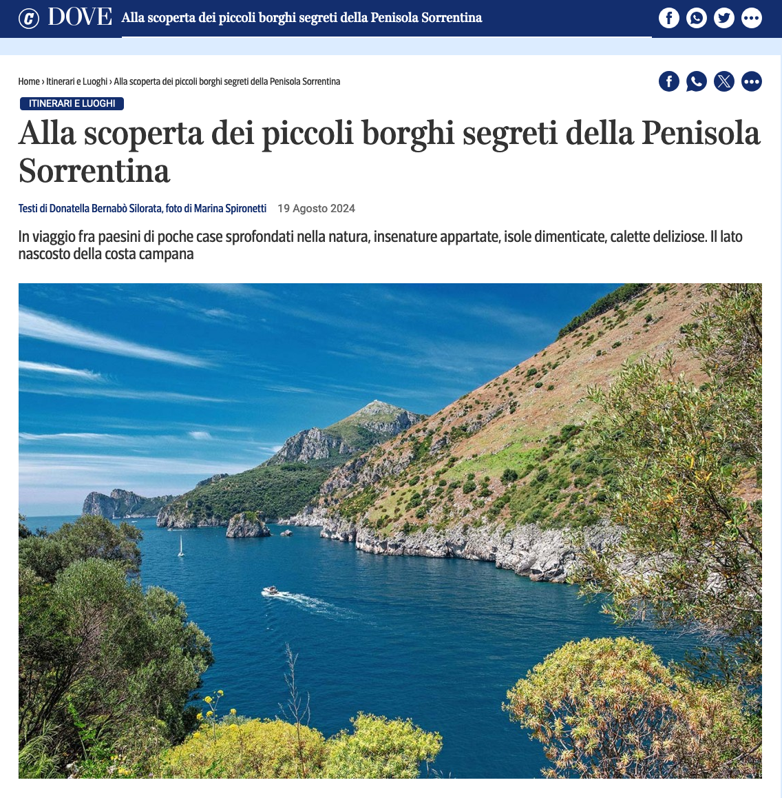 A scenic view of a blue bay along the rocky, green Sorrento Peninsula with a small boat traveling on the water.