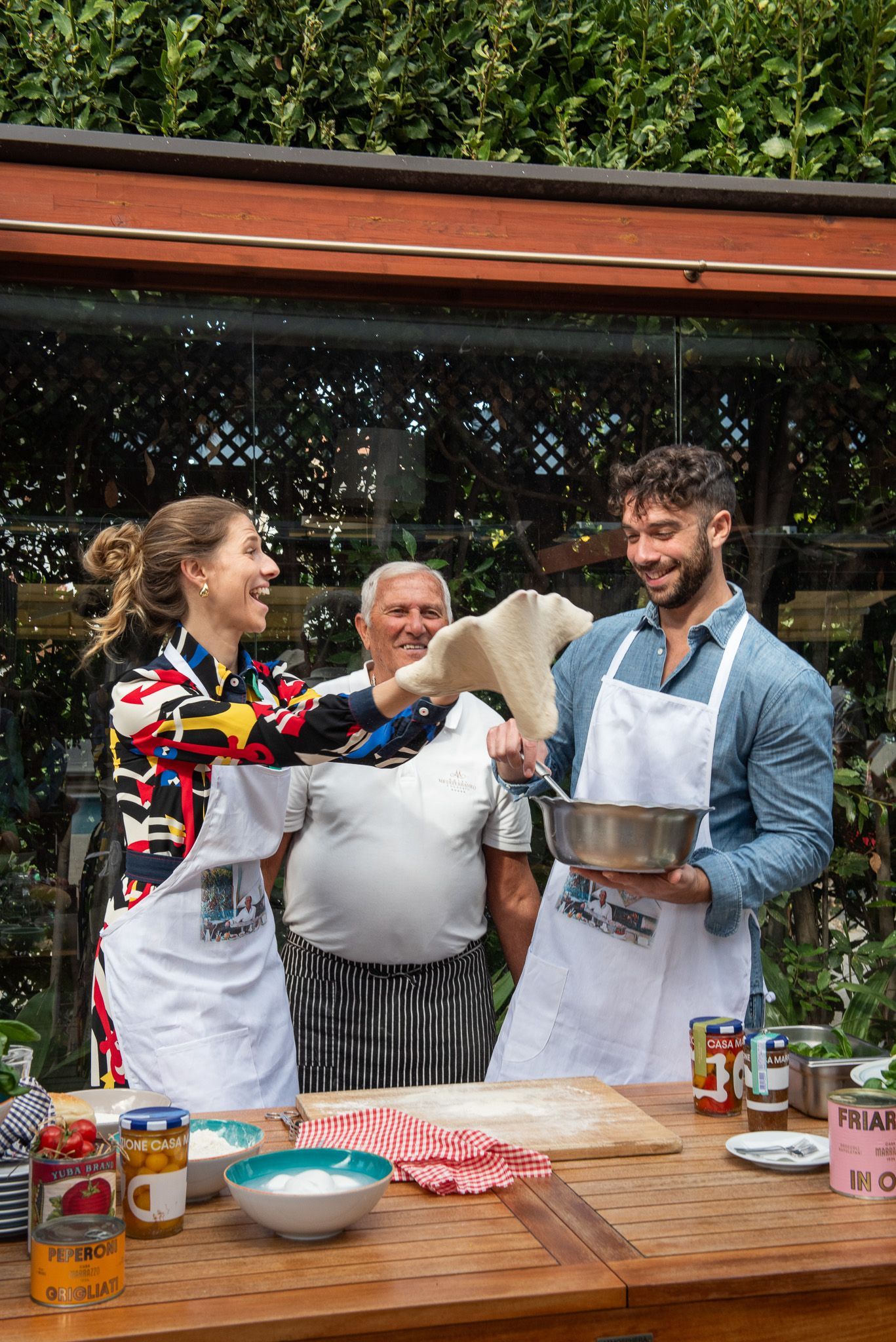 Tre persone con il grembiule partecipano a un corso di cucina come esperienza a Sorrento.