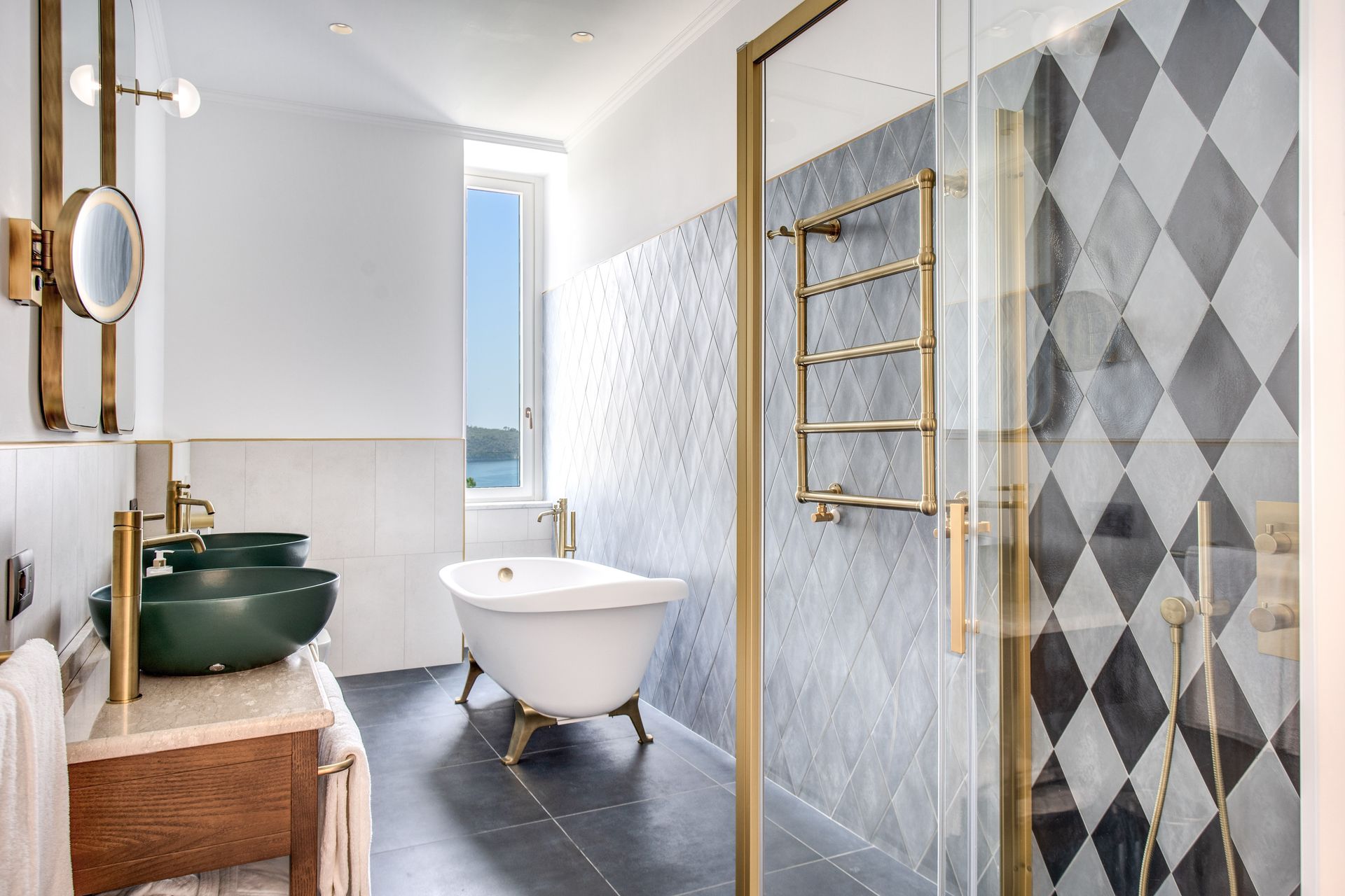 Un bagno con due lavabi a ciotola verdi, una vasca da bagno bianca freestanding e una doccia con piastrelle a rombi bianchi e neri.
