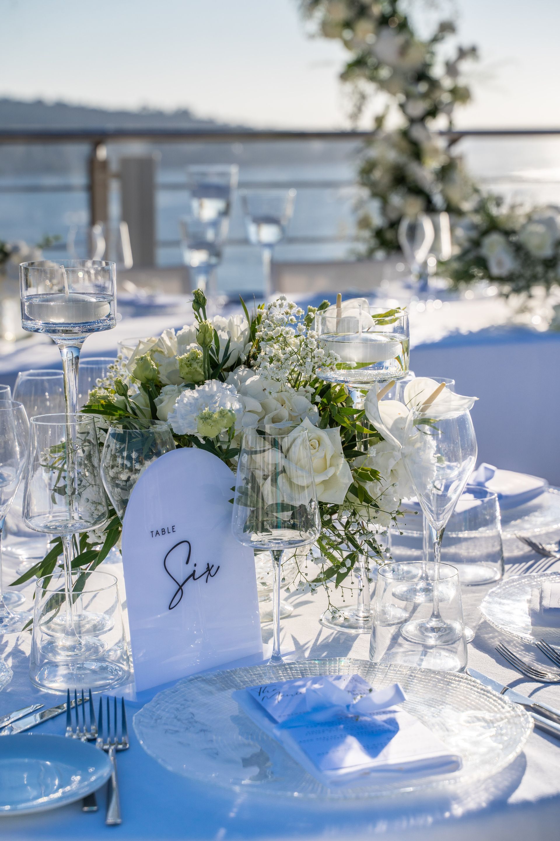 Un allestimento da tavola per un matrimonio all'aperto con fiori bianchi, un segnaposto con il numero 