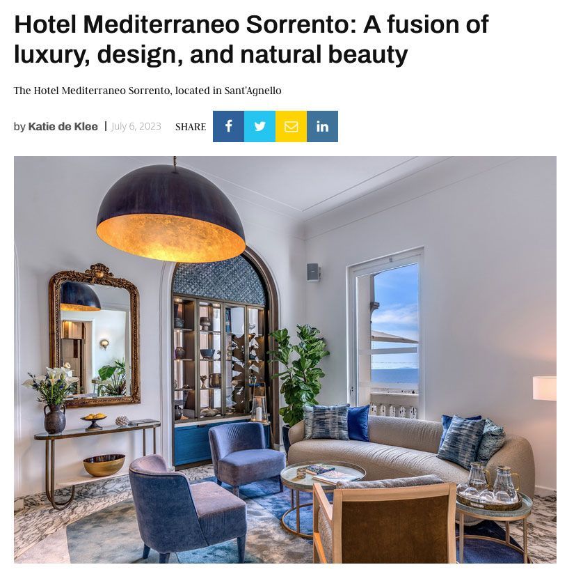A sophisticated hotel lounge with blue velvet armchairs, a beige sofa, gold accents, and a large arched window with a view.