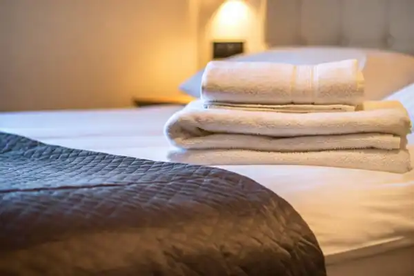 A bed with a stack of towels on top of it.
