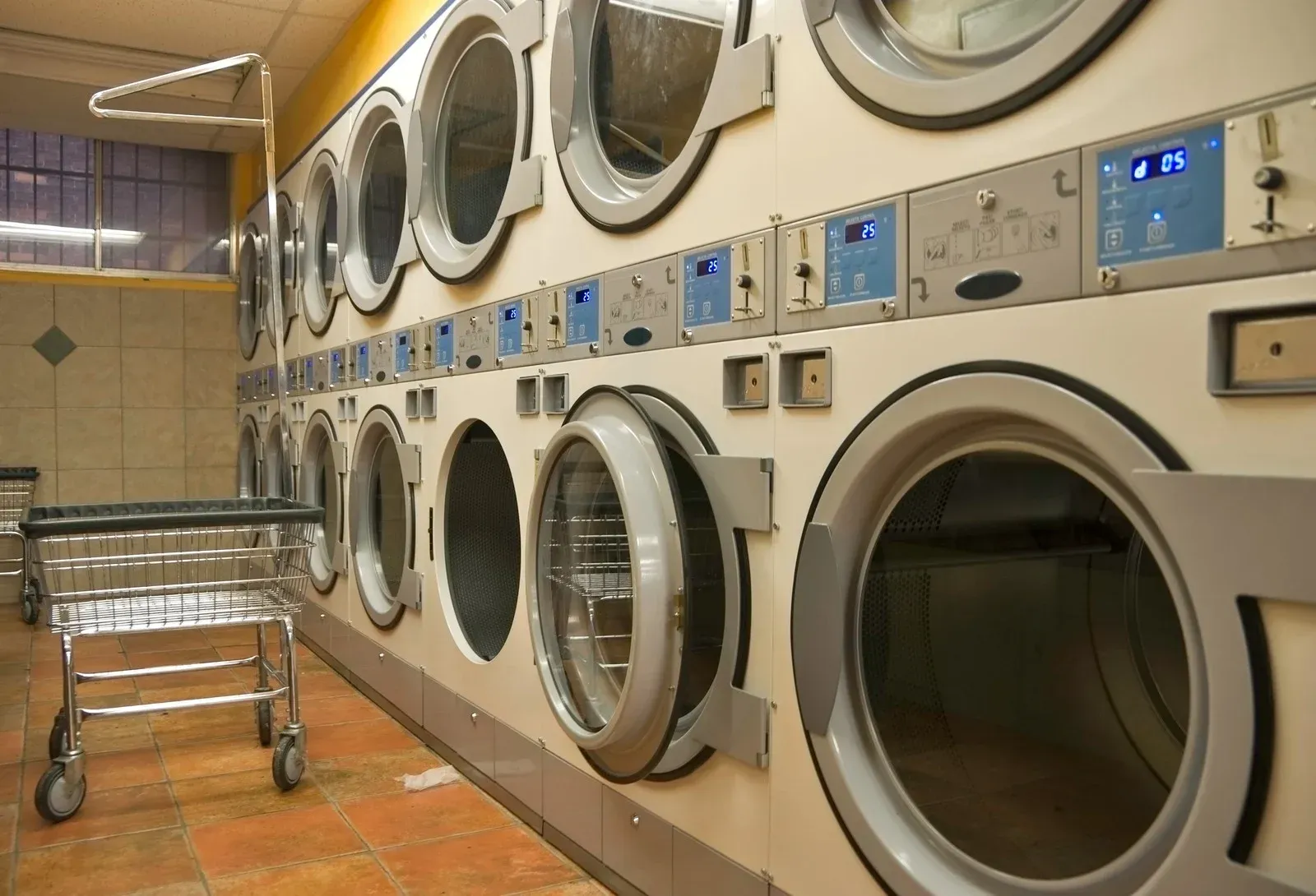 Person placing a teal towel into a white washing machine.