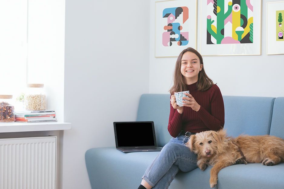 A woman is sitting on a couch with a dog and a laptop. A woman is sitting on a couch with a dog and a laptop.