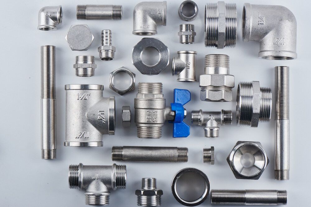 A Bunch Of Stainless Steel Pipes And Fittings On A White Surface — C.J Honeysett Plumbing In Peak Hill, NSW