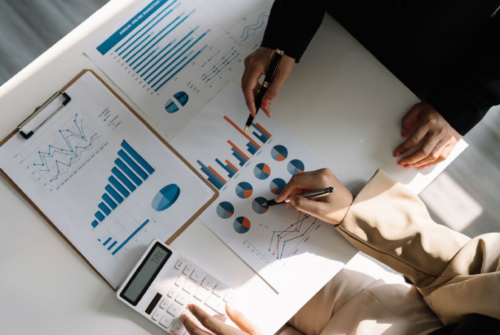 A group of people are sitting at a table looking at graphs and charts.