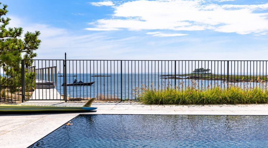 Black metal residential pool fence overlooking an ocean bay.