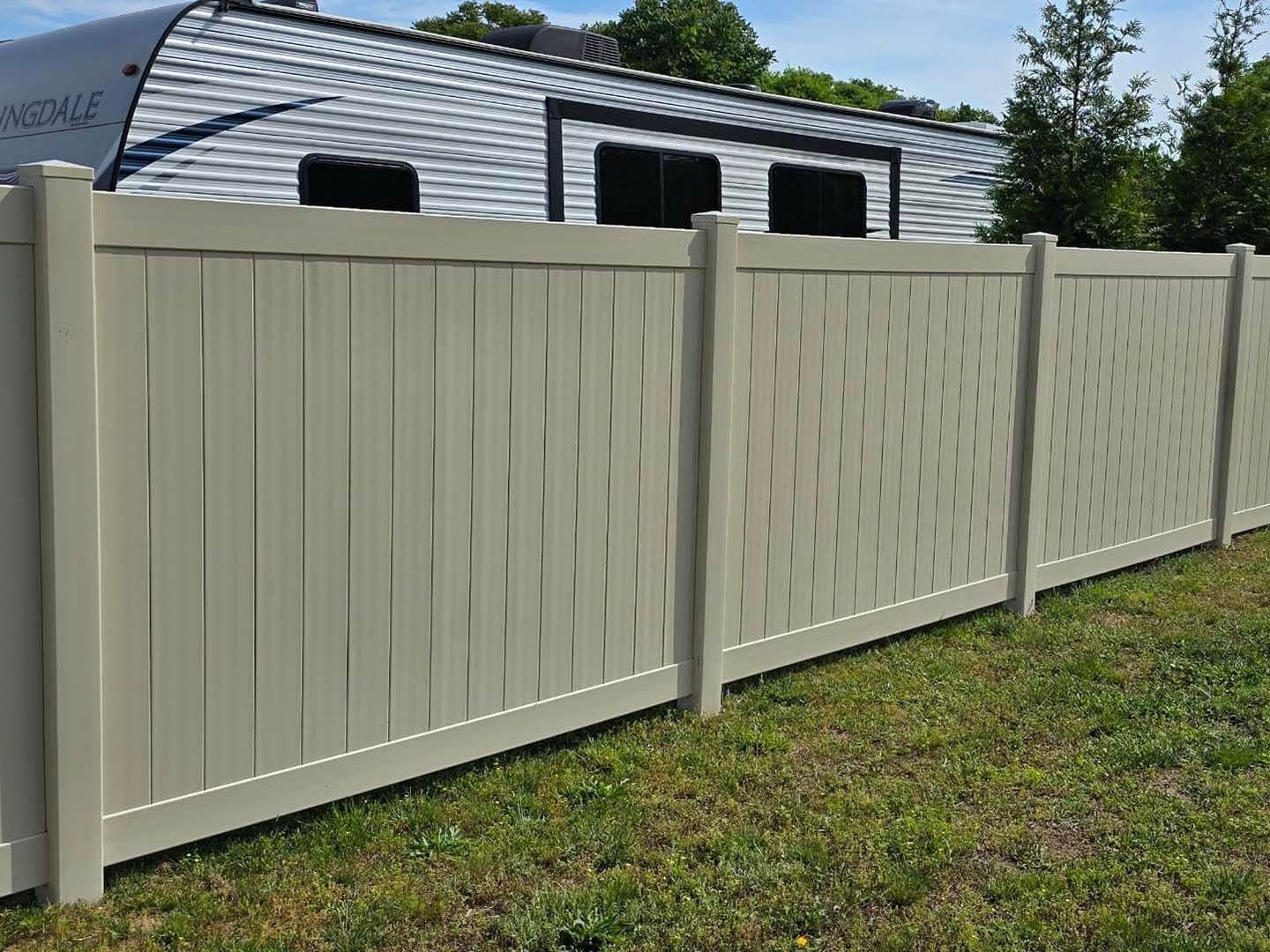 Beige vinyl fence with a trailer in the background.