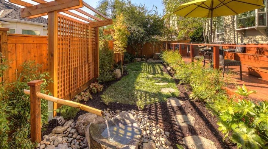 Landscaped backyard featuring a wooden privacy fence, lattice screen, and stone walkway.