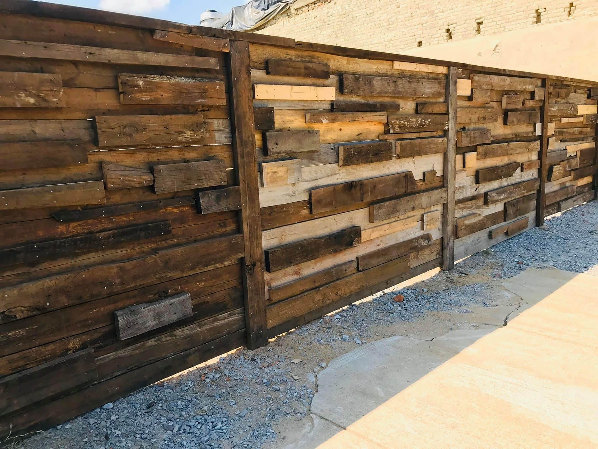 Rustic wooden fence constructed from reclaimed boards, outdoors.