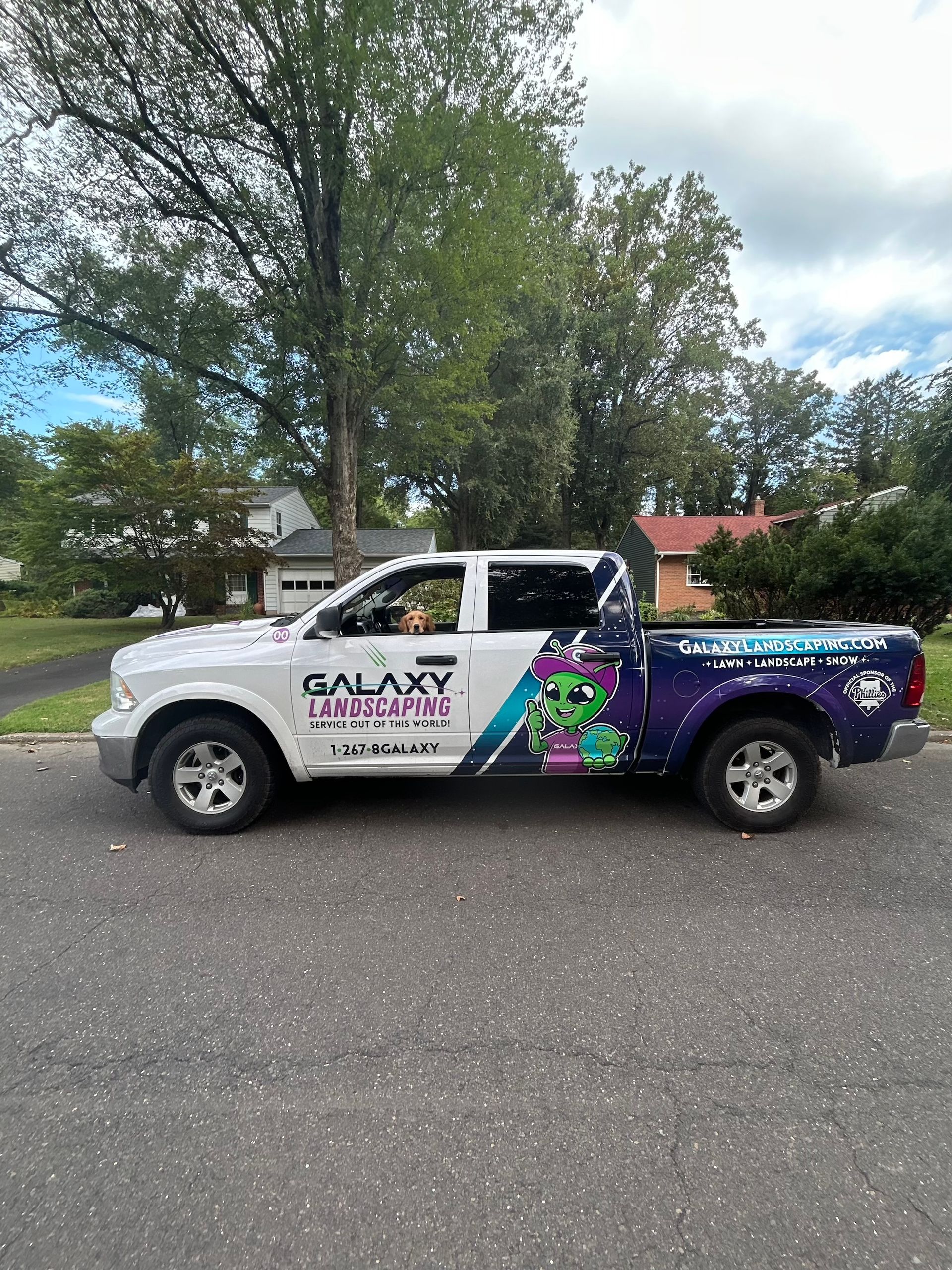 White truck with Galaxy Landscaping graphics parked on a street.