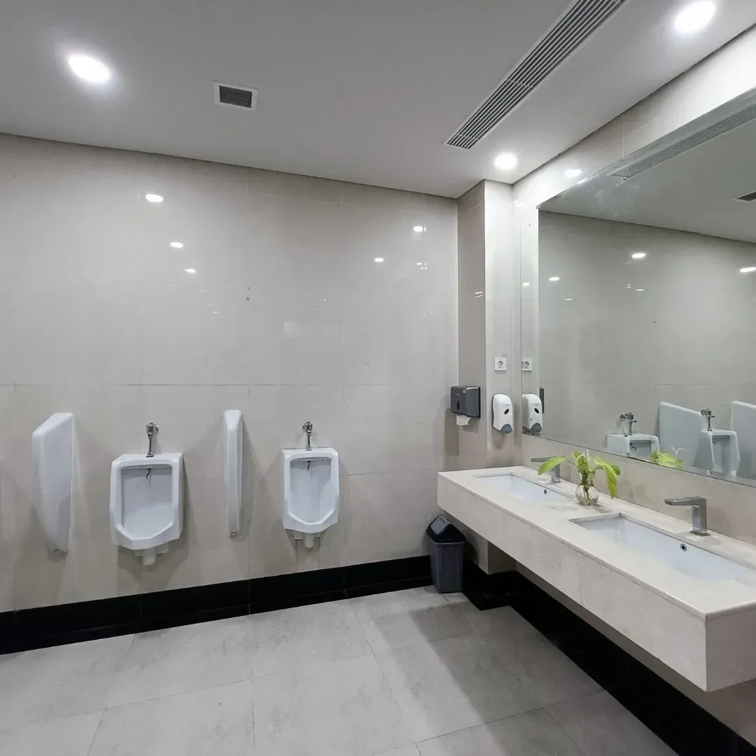 Modern public restroom with white walls, urinals, sinks, and a large mirror