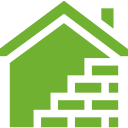 A green house with a brick wall underneath it.