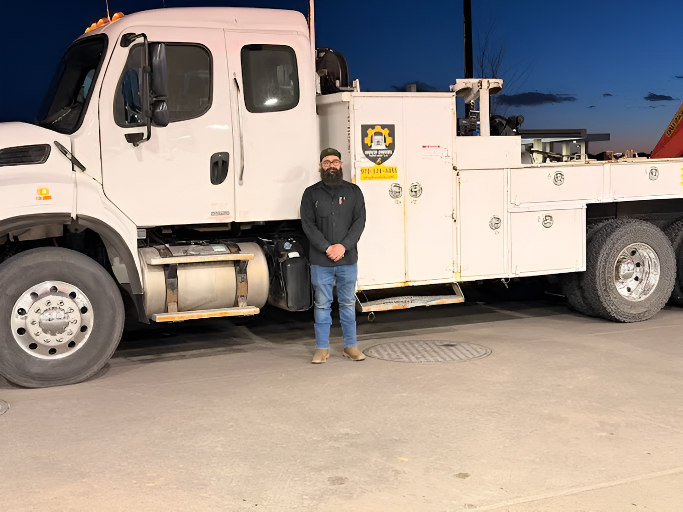 Person standing beside a white utility truck at dusk