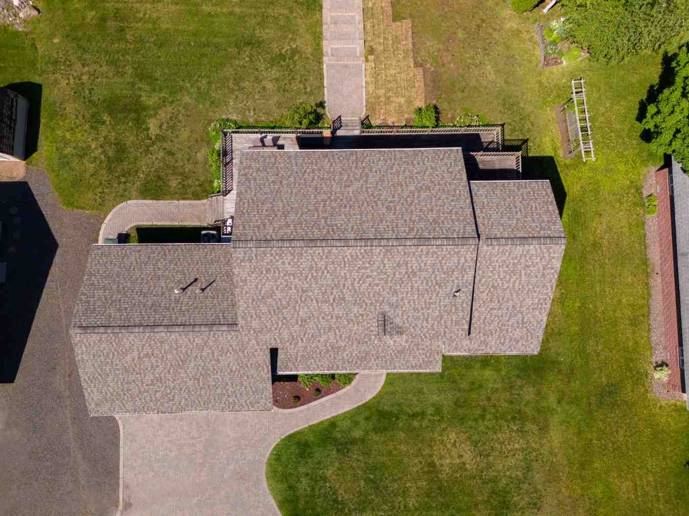 An aerial view of a house with a gray roof and a driveway.