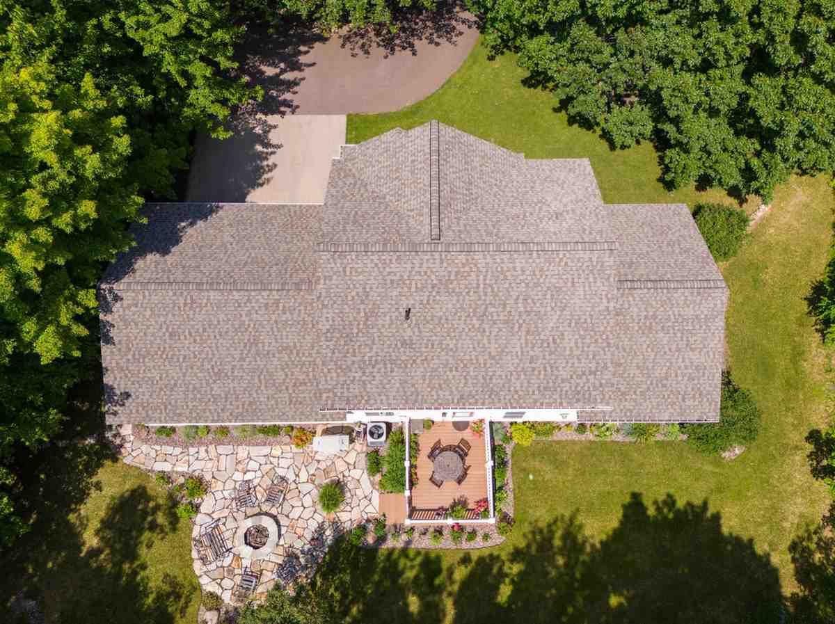 An aerial view of a house with a fire pit in the backyard surrounded by trees.