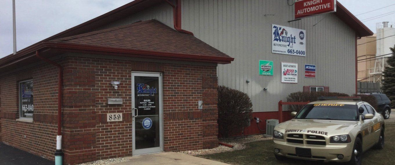 A car is parked in front of a brick building.