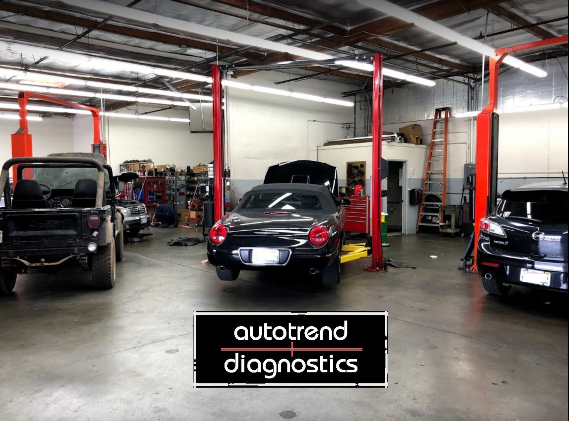 A car is on a lift in a garage with a sign that says autotrend diagnostics