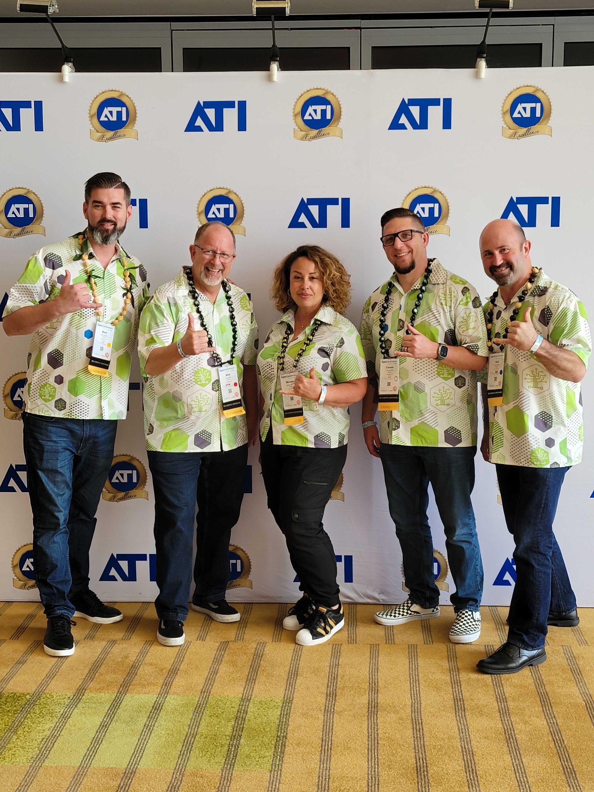 A group of people standing in front of a wall that says ati