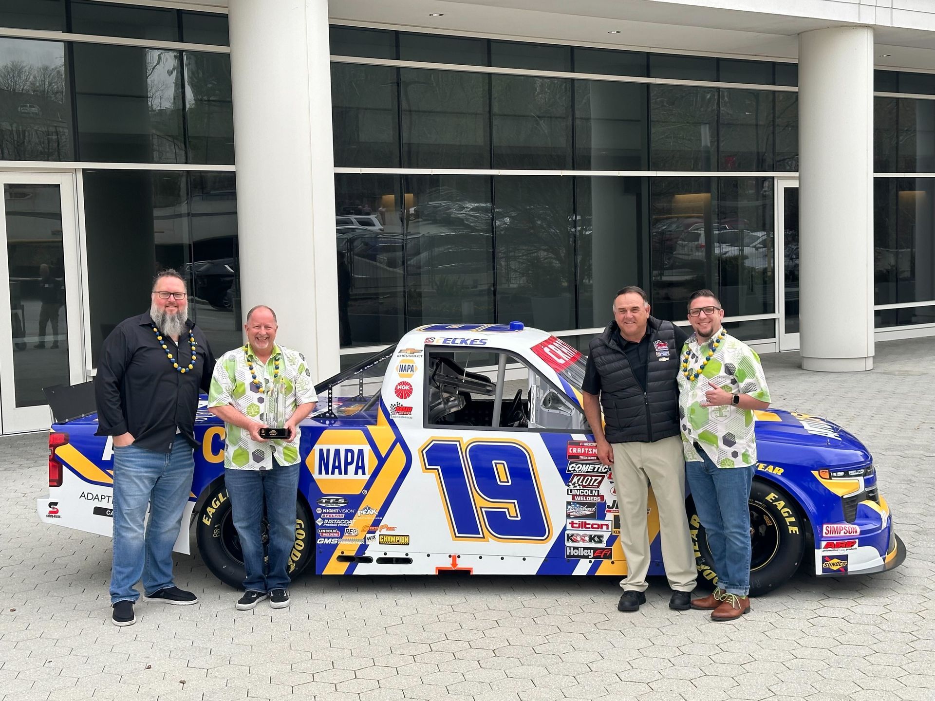 A group of men are standing in front of a napa truck.
