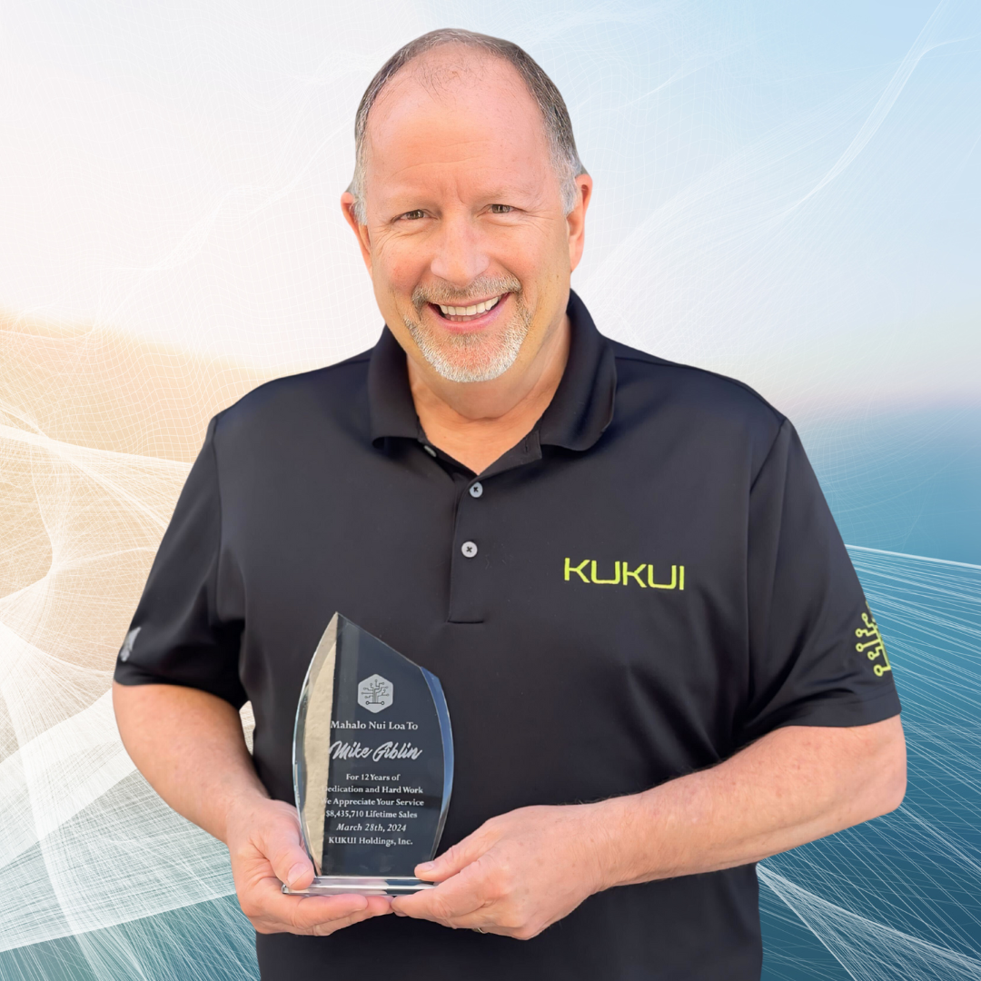 A man in a kukui shirt is holding a trophy