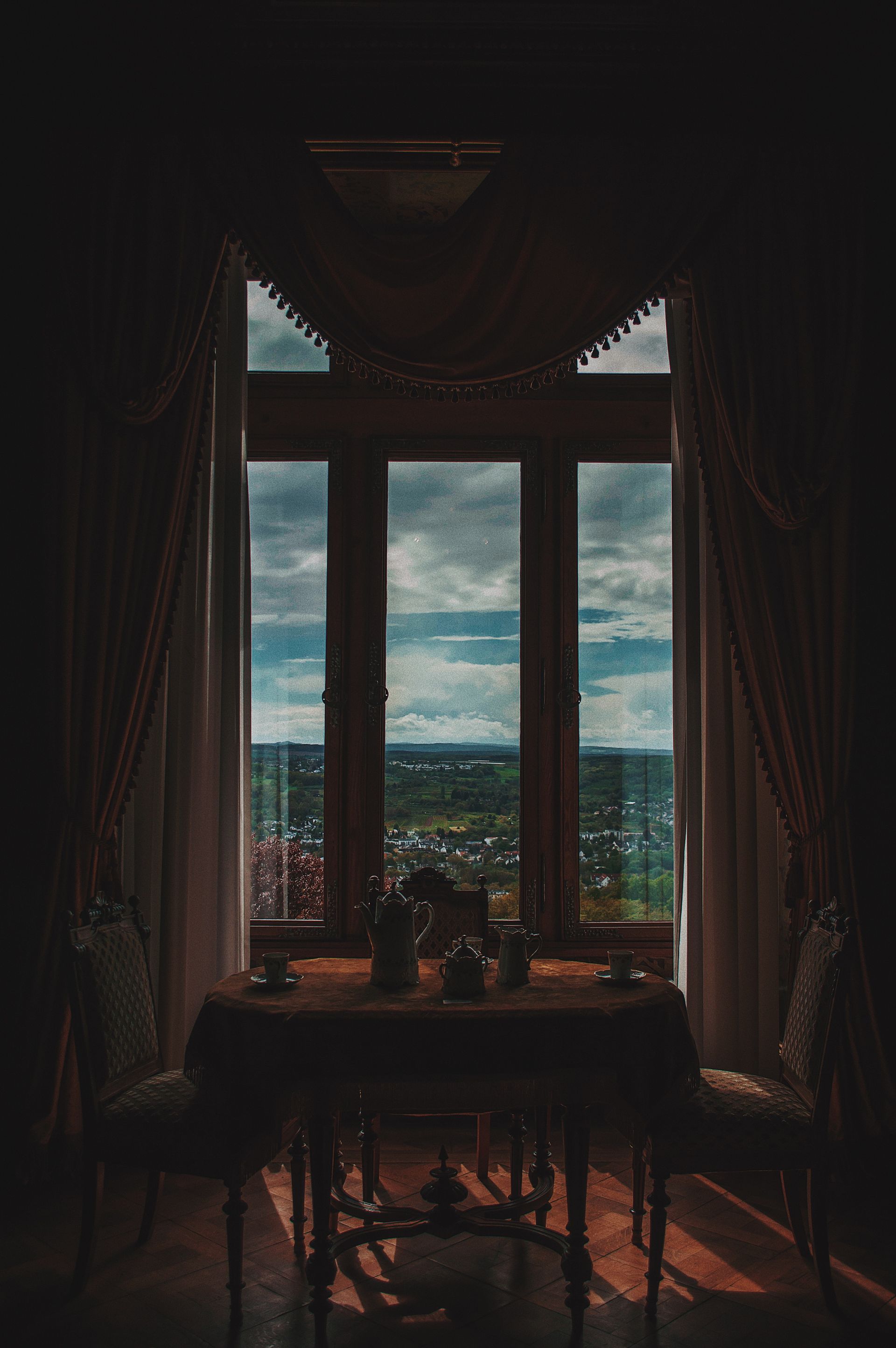 A dining room with a table and chairs and a large window with a view of the ocean.