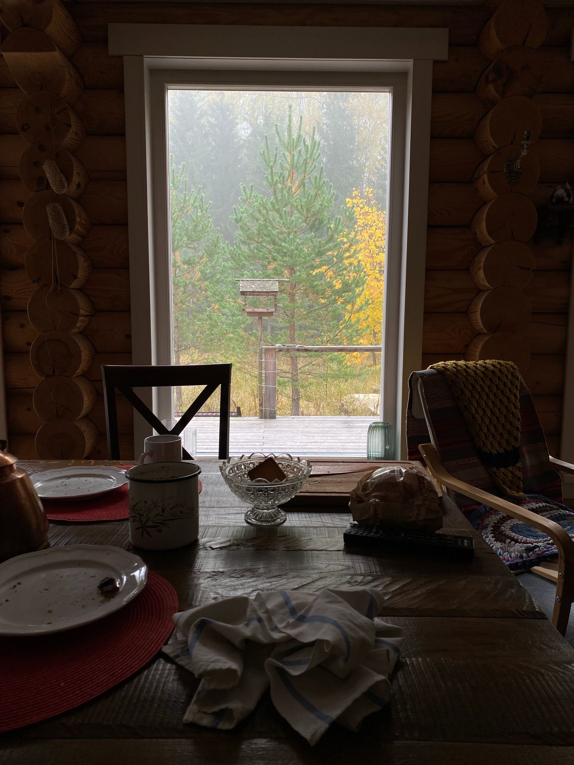 A wooden table with plates and napkins on it in front of a window.
