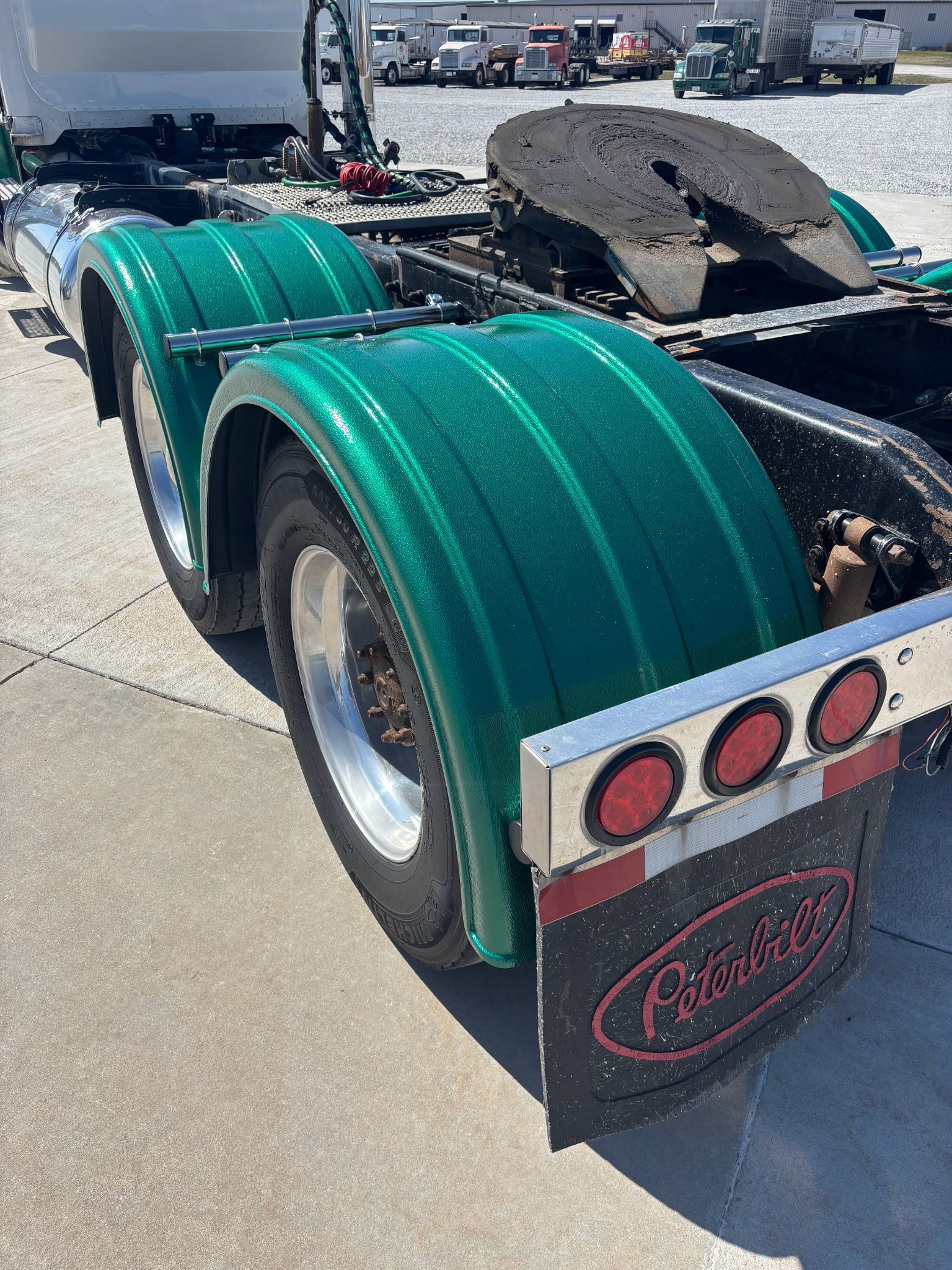 A semi truck with green fenders is parked on the side of the road.