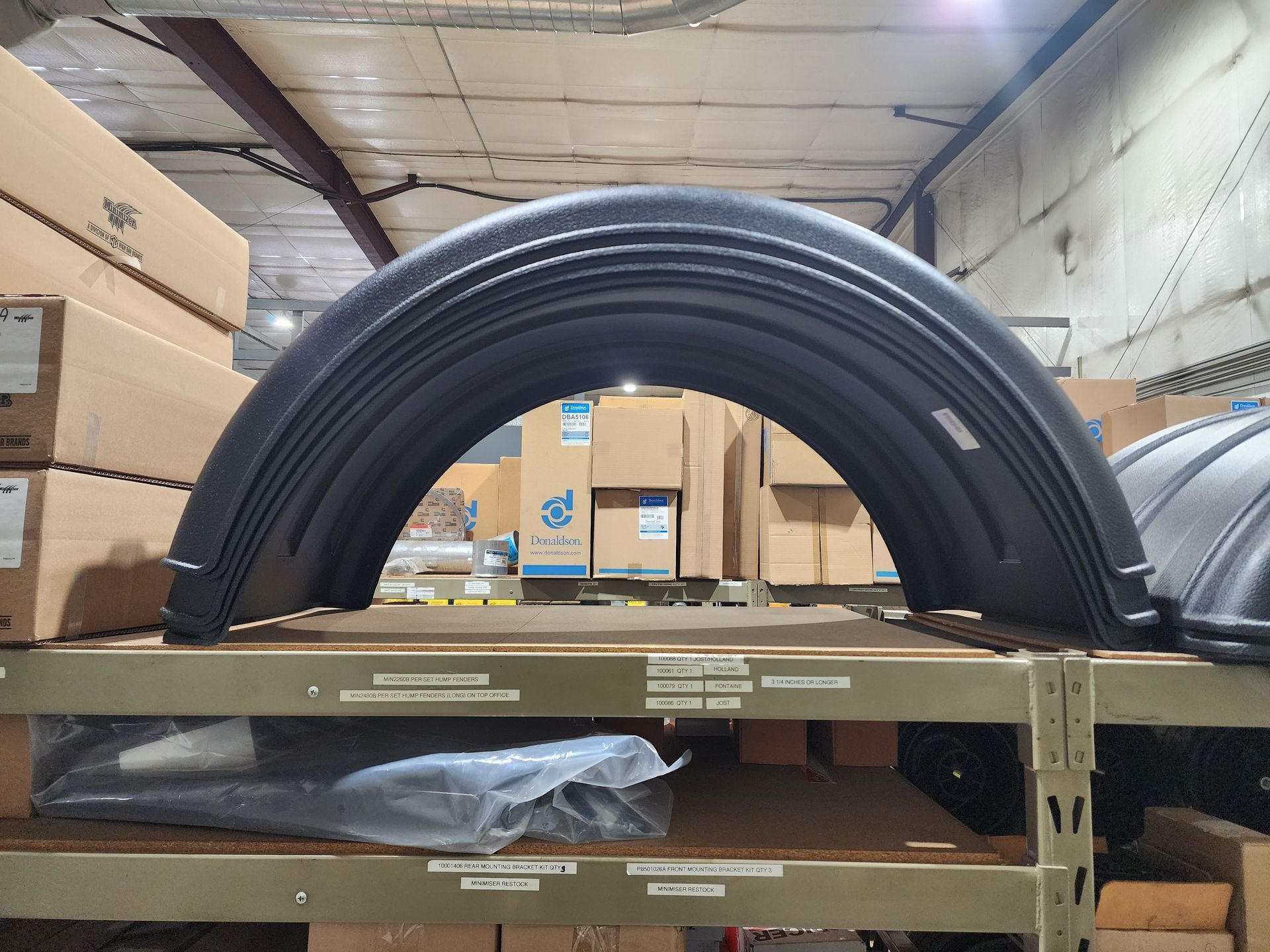 A large fender is sitting on top of a shelf in a warehouse.