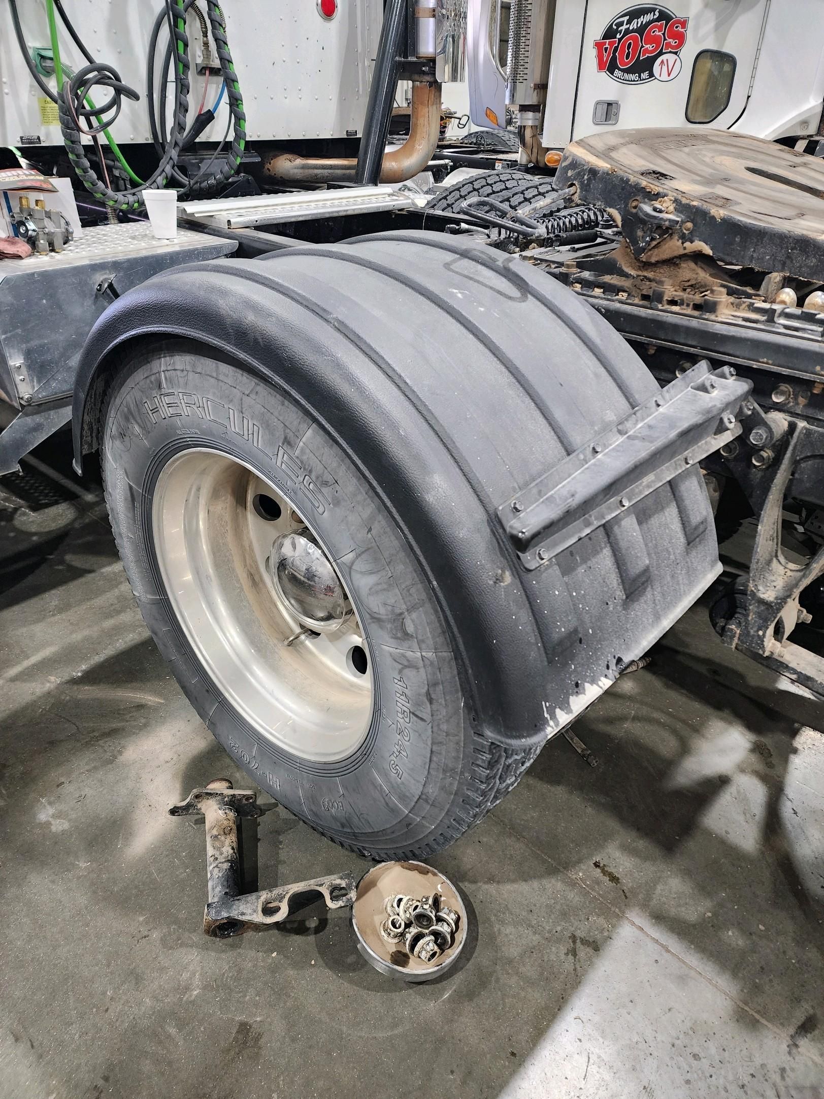A close up of a truck 's fender and tire in a garage.