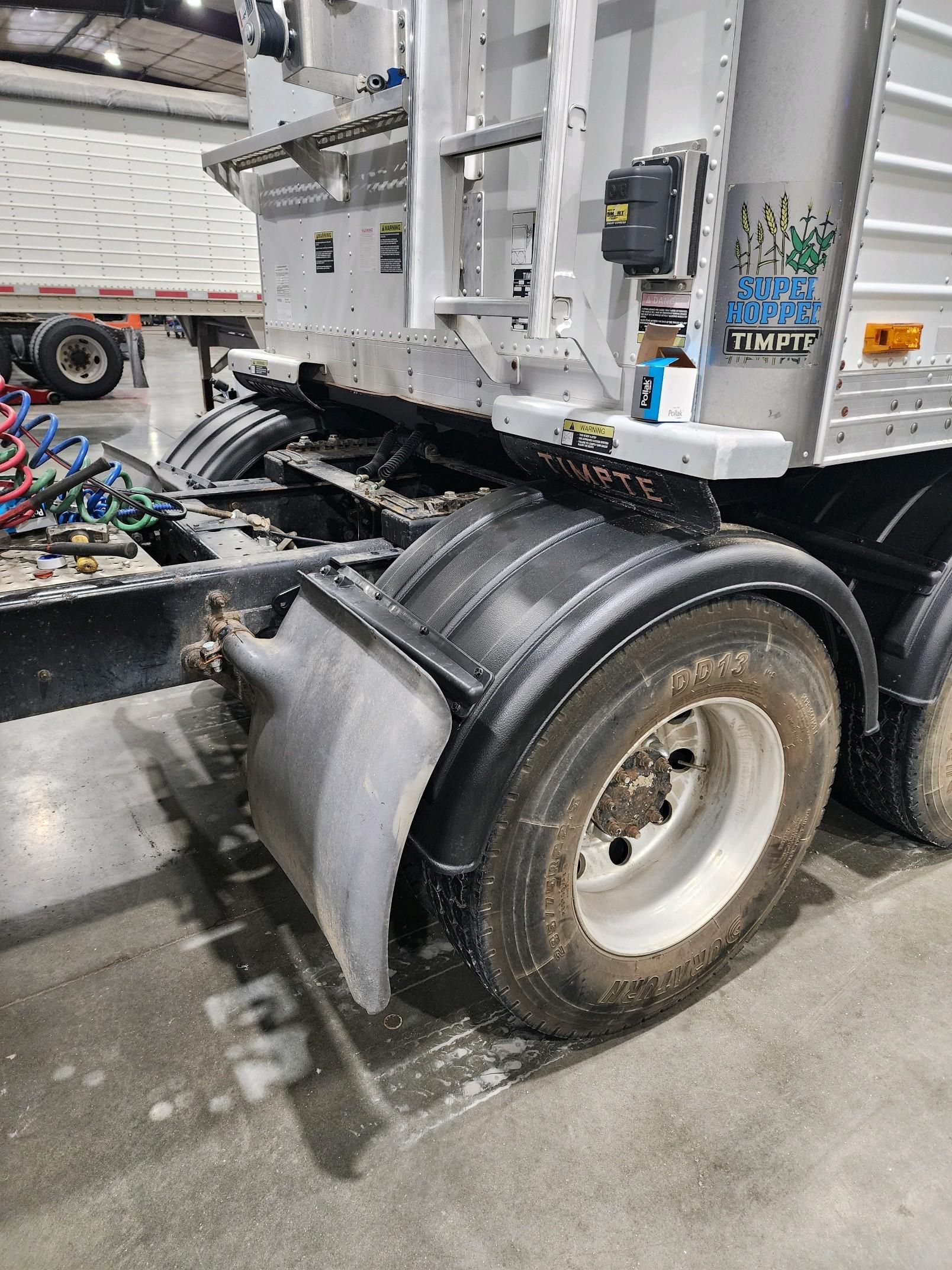 A semi truck with a trailer attached to it is parked in a warehouse.