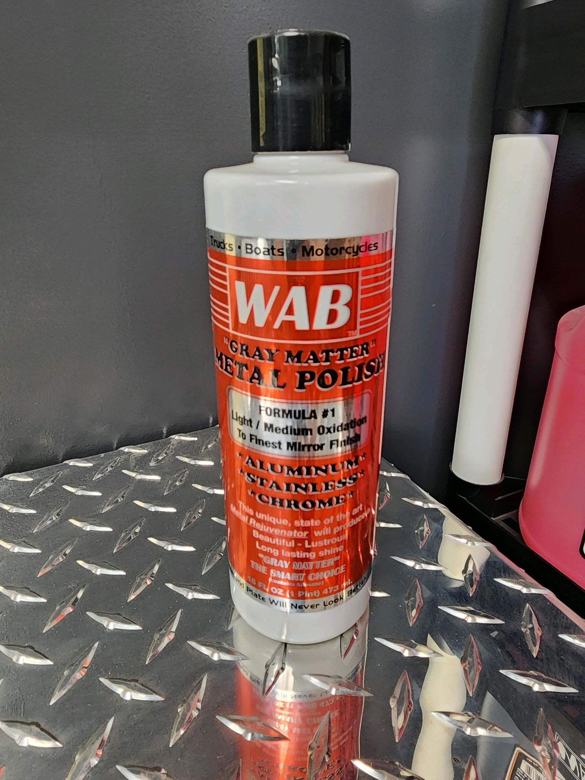 A bottle of wab metal polish is sitting on a metal surface.