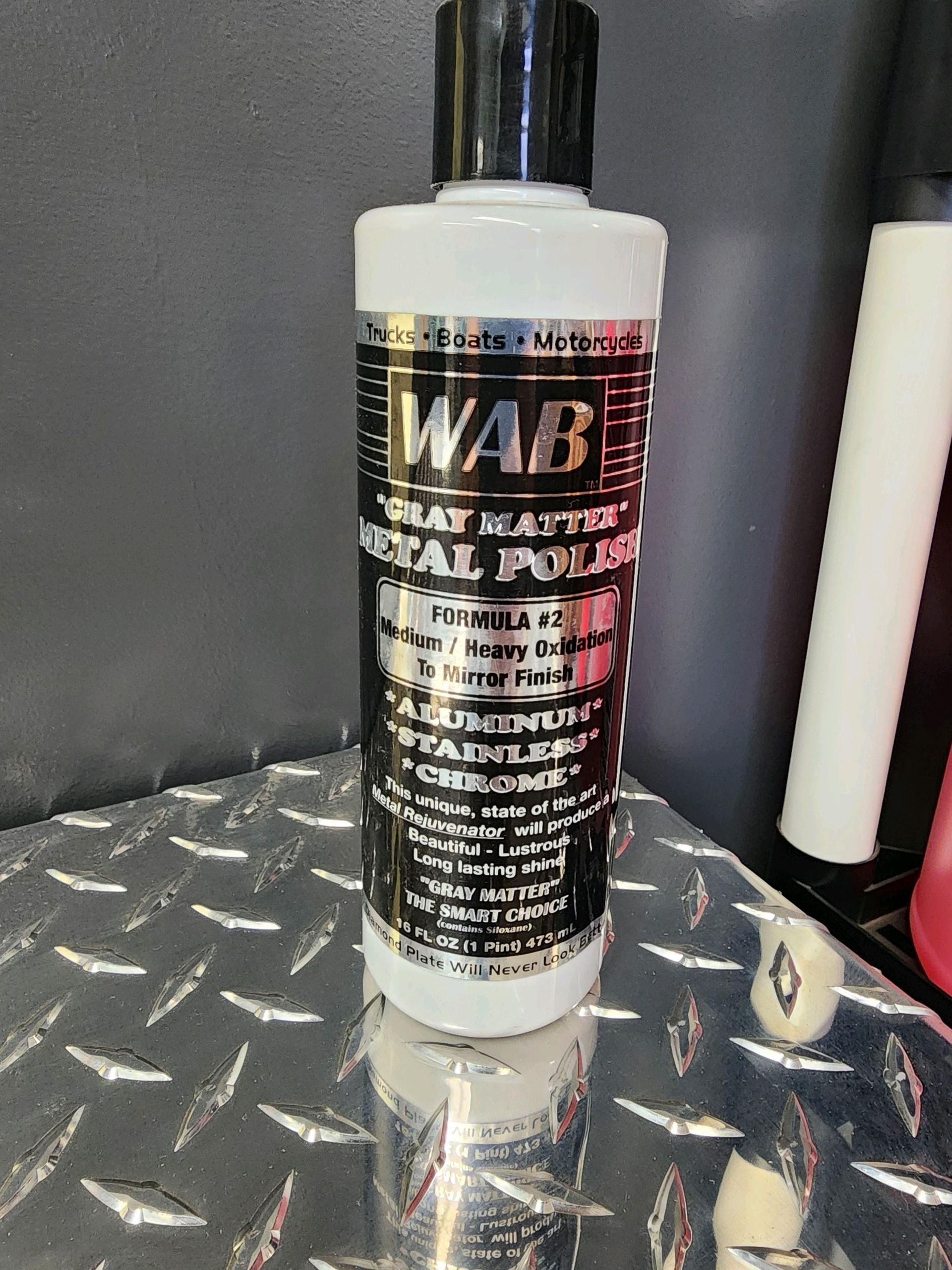 A bottle of wab metal polish is sitting on a metal surface.