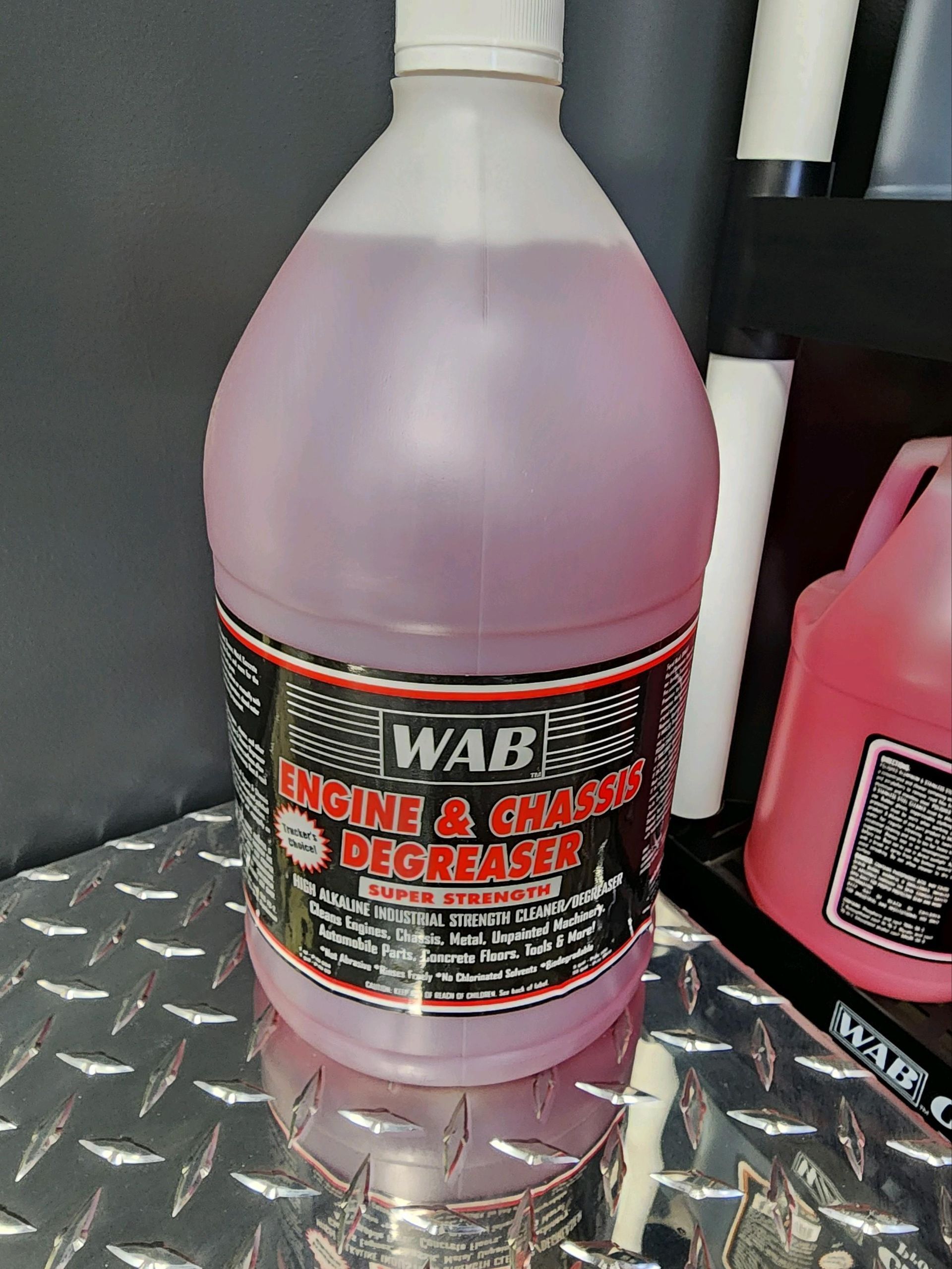 A bottle of engine cleaner is sitting on a metal surface.
