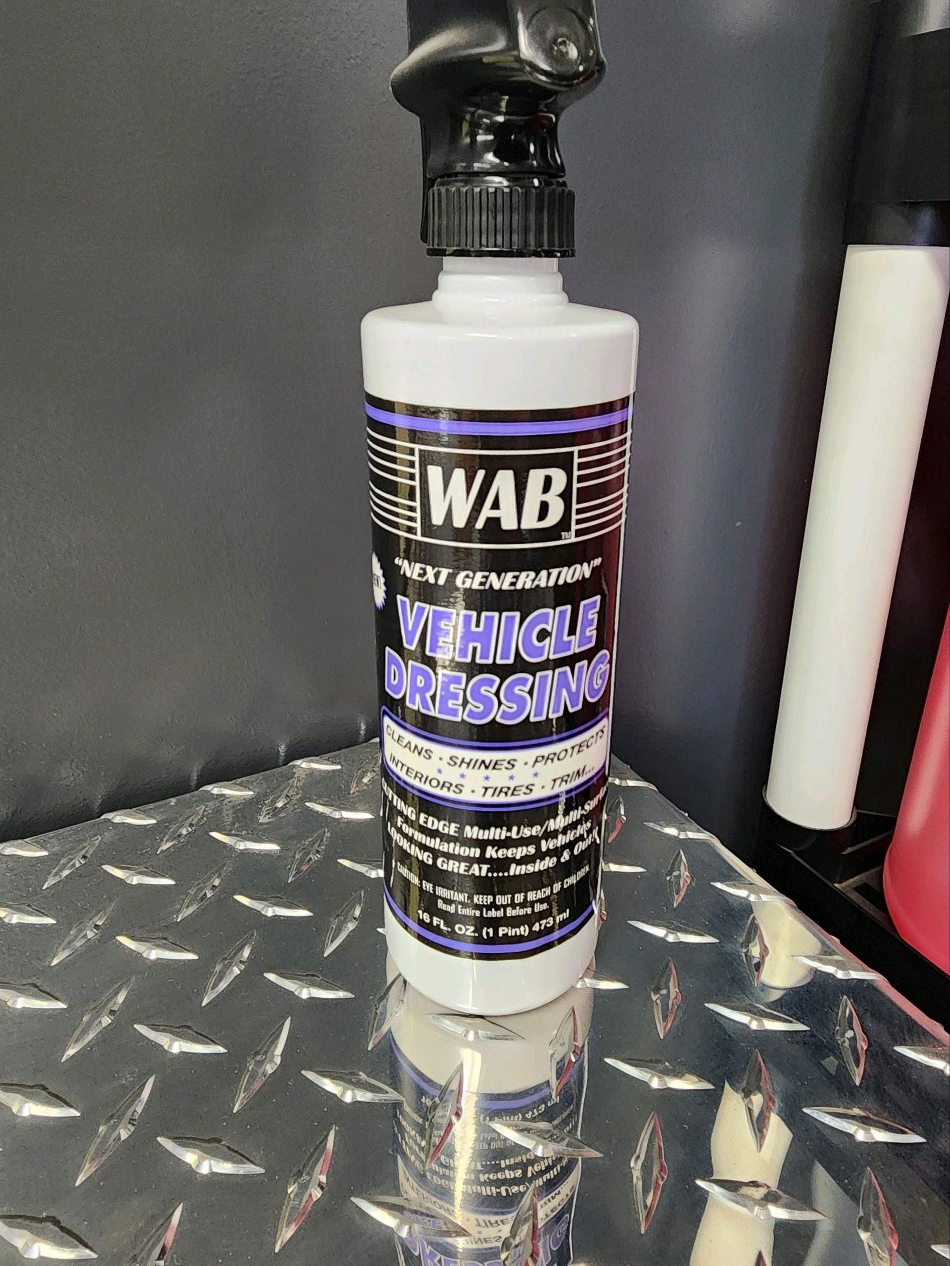 A bottle of vehicle dressing is sitting on a metal surface.