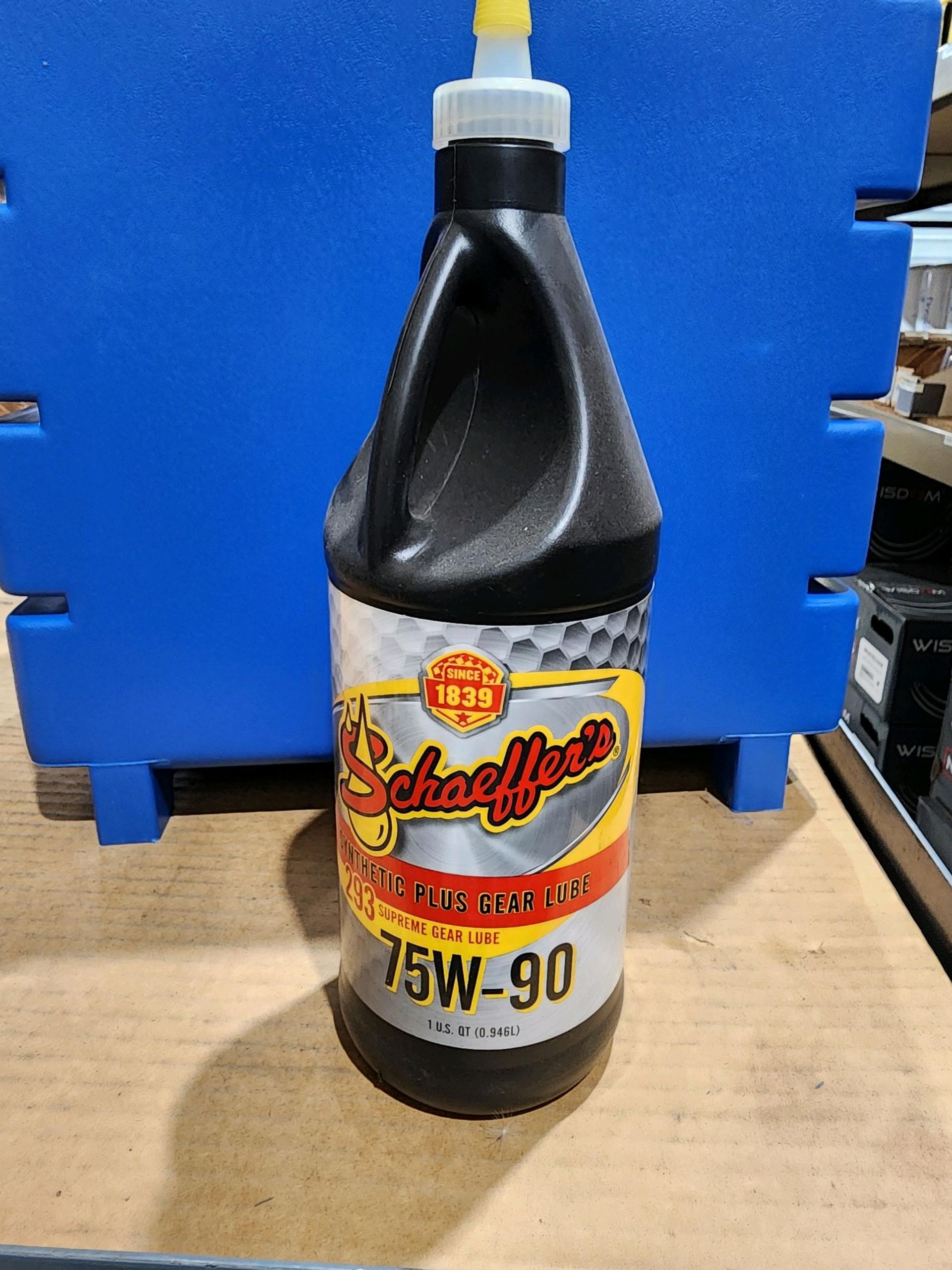 A bottle of 75w-90 is sitting on a wooden table.