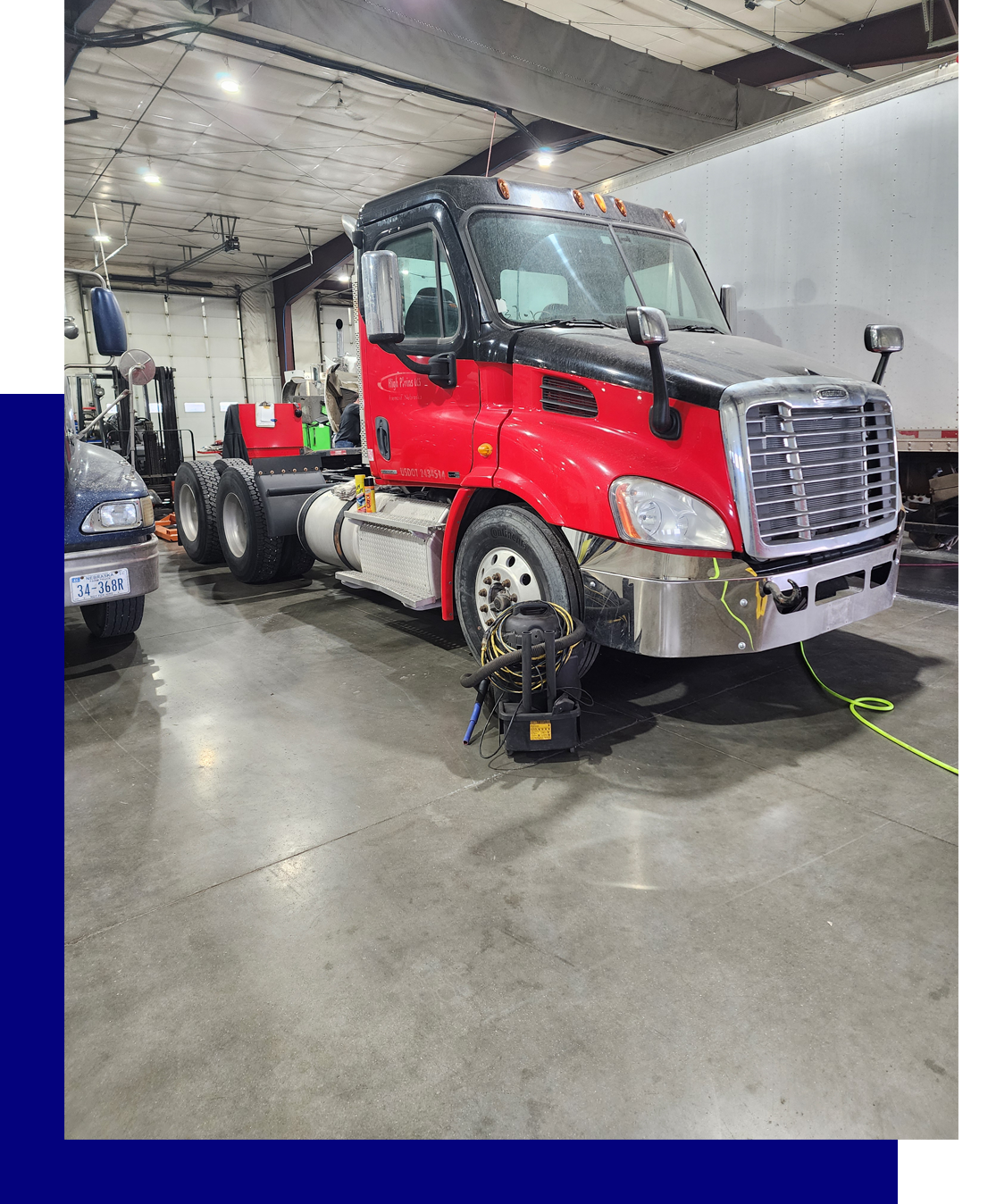 A red semi truck is parked in a garage.