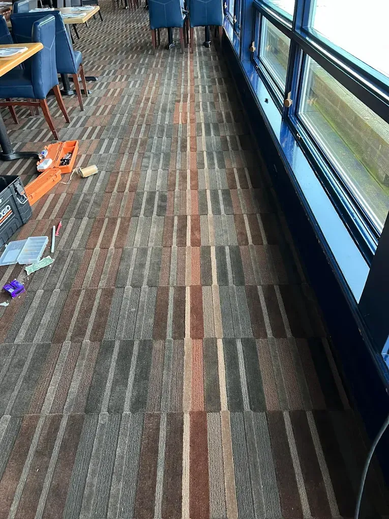 Tiled floor with a vertical stripe design in a room with blue chairs, a window, and some tools.