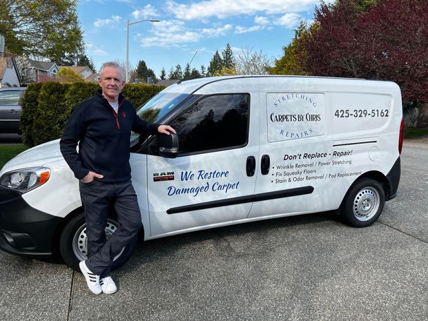 Man stands next to a white van with business logo