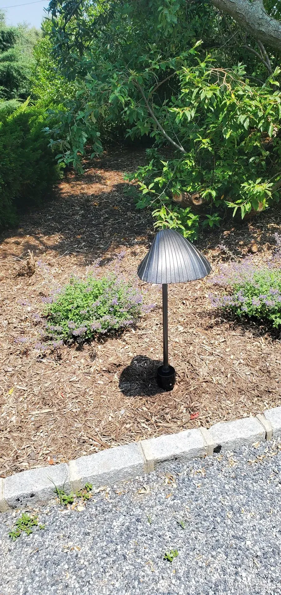 A small lamp is sitting in the middle of a garden.