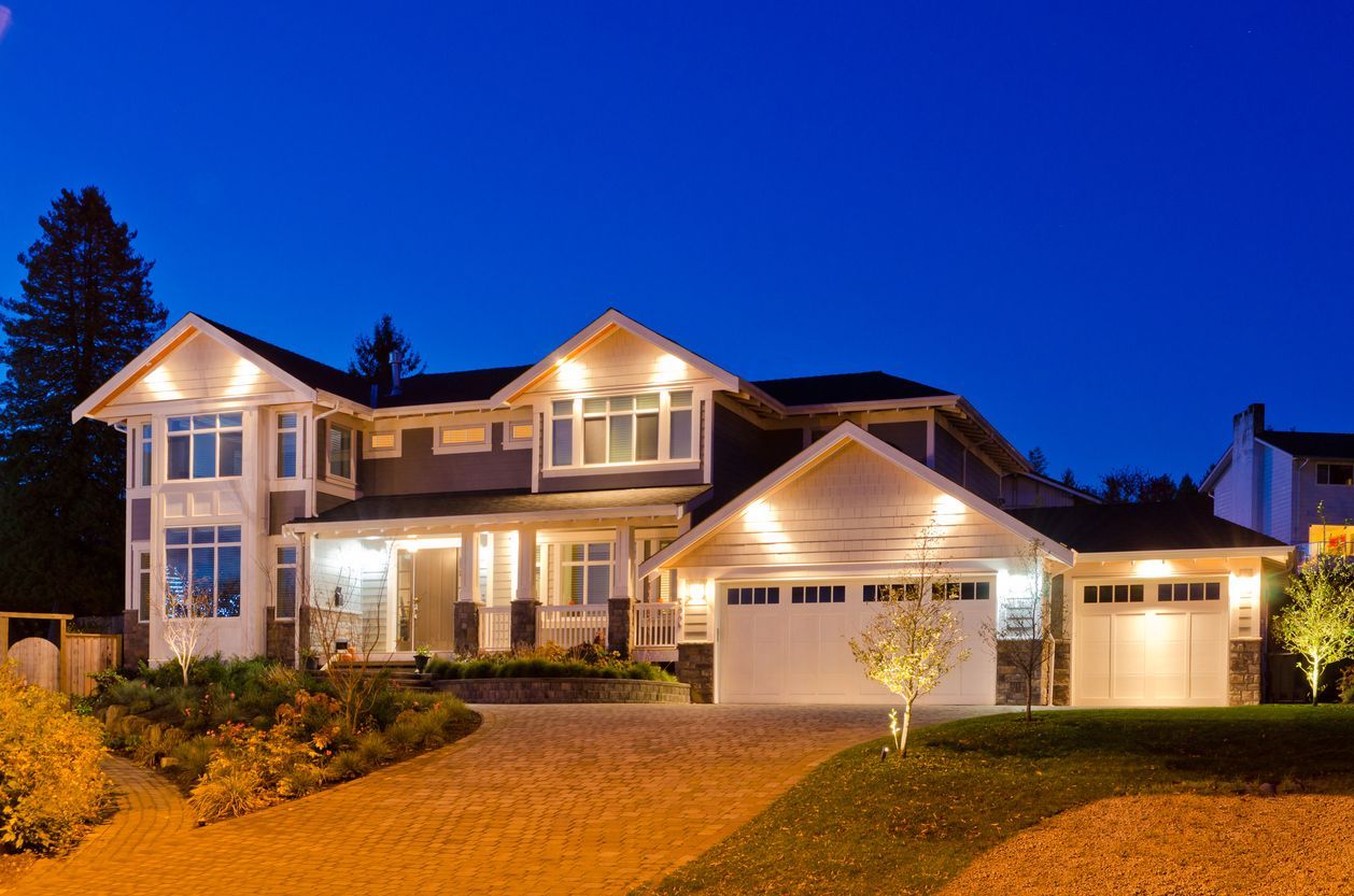 A large house with two garages is lit up at night.