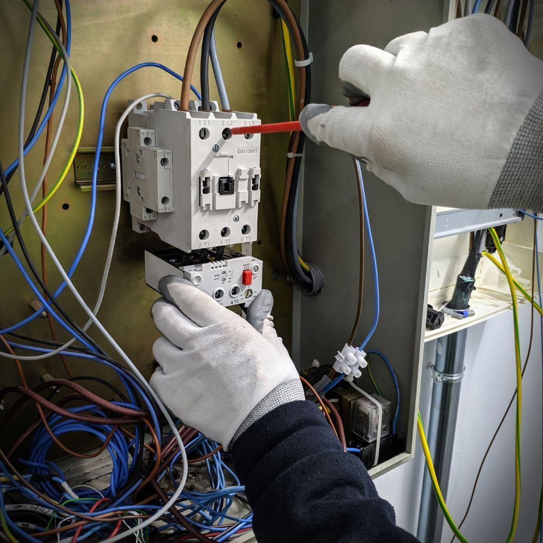 A person is working on an electrical box with a screwdriver
