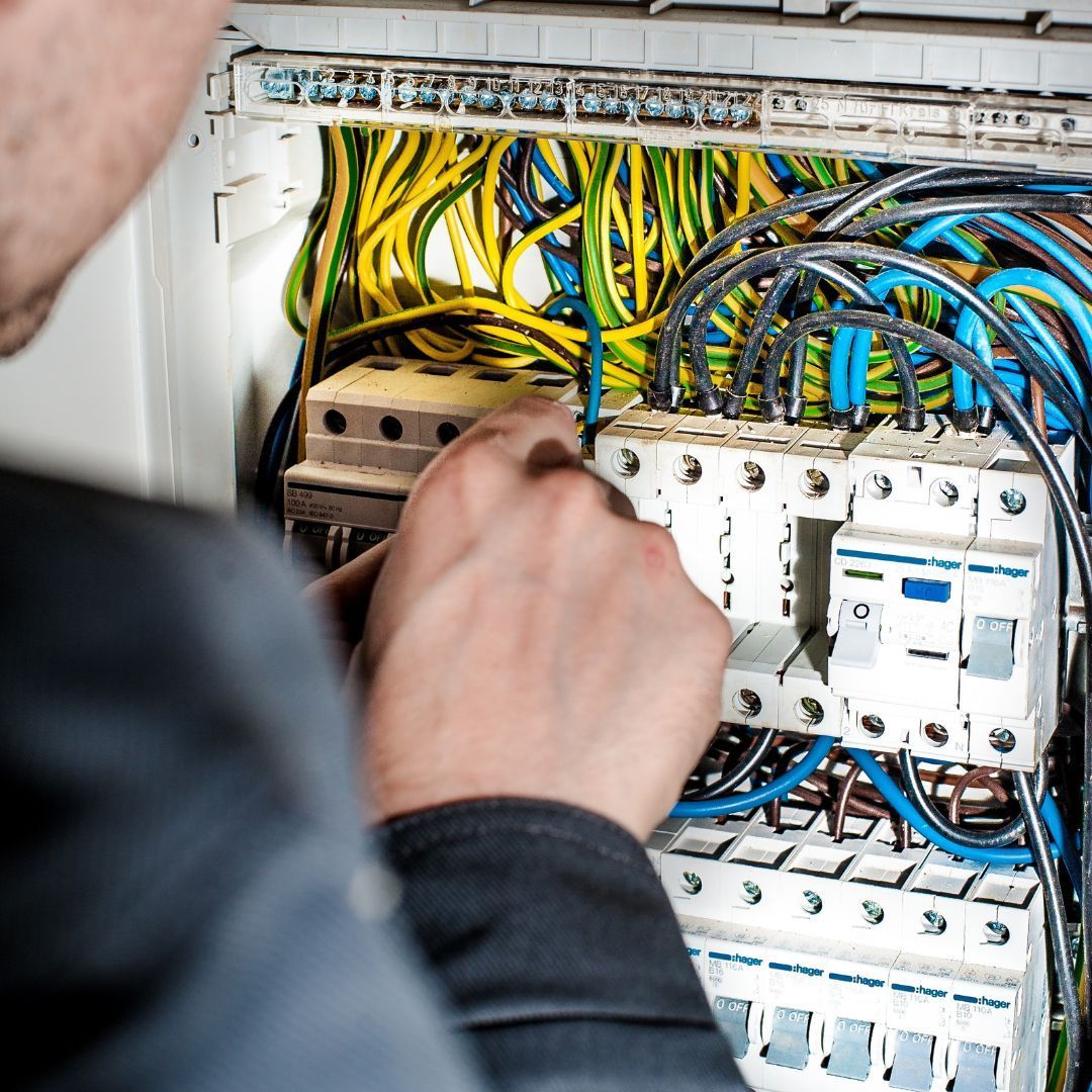 A man is working on an electrical box with a screwdriver.