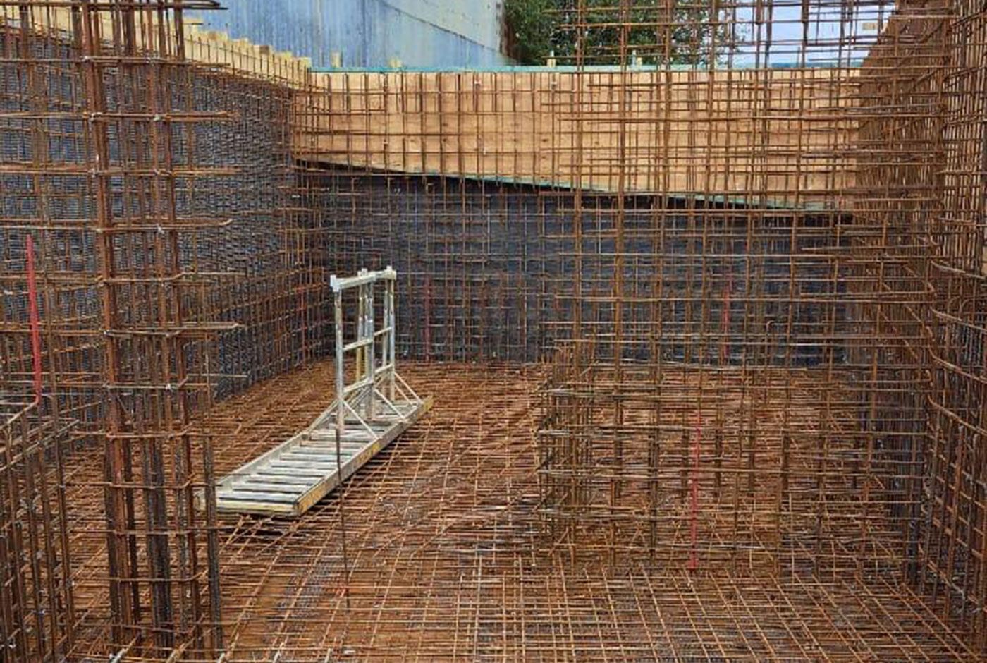 Dense steel rebar framework at a construction site viewed within the structure itself.