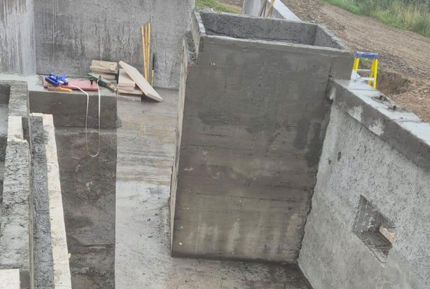 Construction site with unfinished concrete walls and scattered tools and materials.