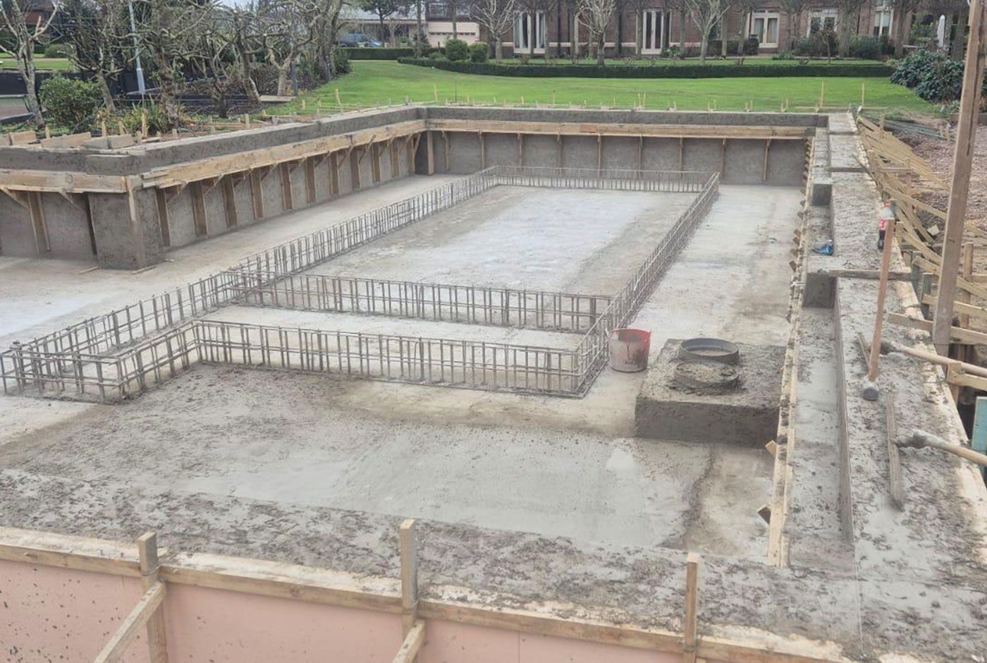 Concrete foundation under construction with rebar framing and surrounding excavation walls.